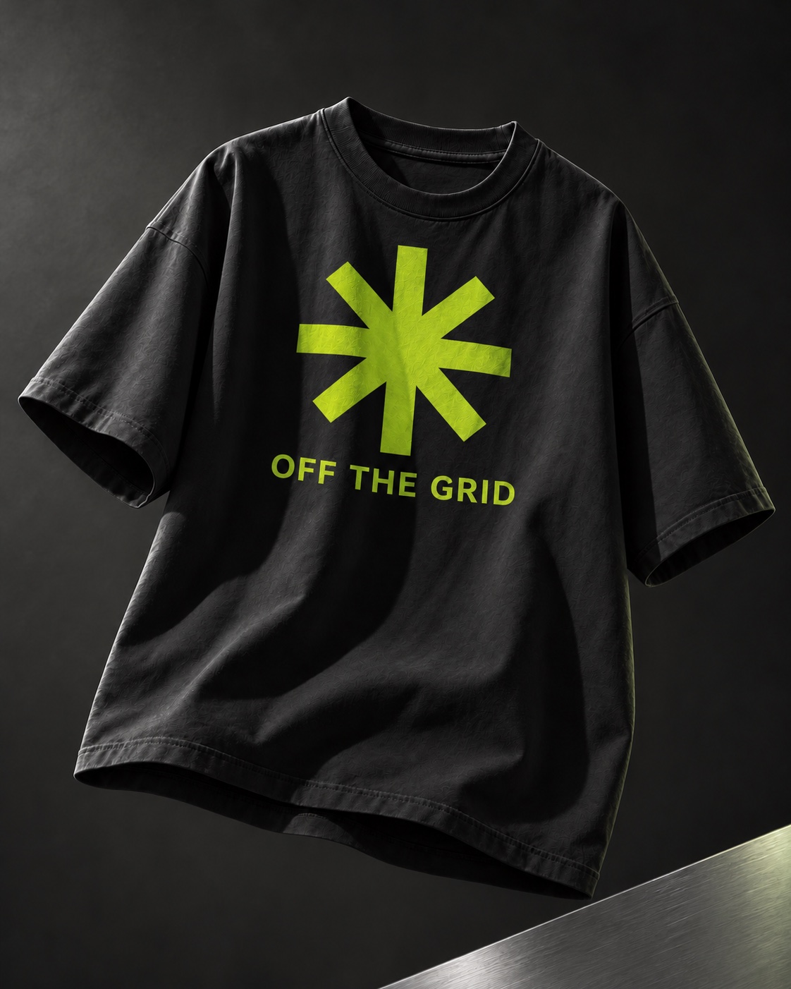 石墨灰摄影背景中的黑色T恤，胸前印着荧光绿星形与OFF THE GRID