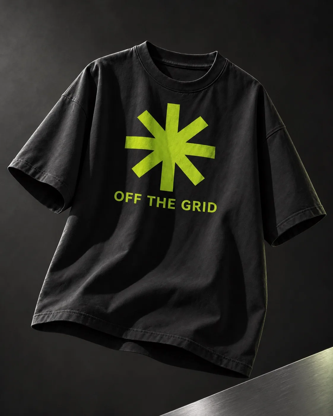 石墨灰摄影背景中的黑色T恤，胸前印着荧光绿星形与OFF THE GRID